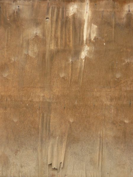 Brown wood texture with light spots of white paint and various dark blemishes and thin cracks.